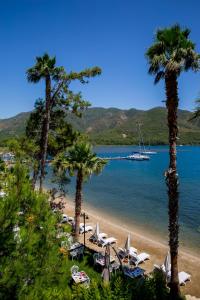 una playa con palmeras y sillas y un barco en el agua en Joya Del Mar Hotel, en Marmaris