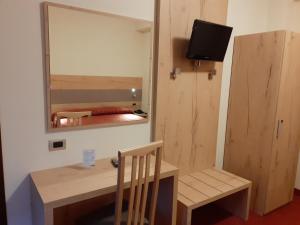 a room with a desk and a mirror and a chair at Hotel Des Alpes in Castione della Presolana