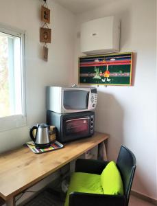 um quarto com uma mesa, um micro-ondas e uma televisão em Glezant em Mitzpe Ramon