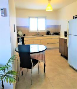 uma pequena cozinha com uma mesa e um frigorífico em Glezant em Mitzpe Ramon