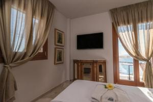 a bedroom with a bed and a tv and windows at Archo Suites Pythagoreio in Pythagoreio