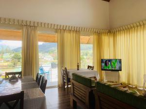a living room with a dining table and a television at Andora Nuwara Eliya in Nuwara Eliya
