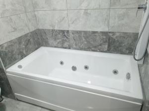 a white bath tub in a bathroom with a tile wall at Center Apartment in Istanbul