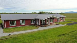 a red house with a gray roof on a green field at Loa's Nest in Hella