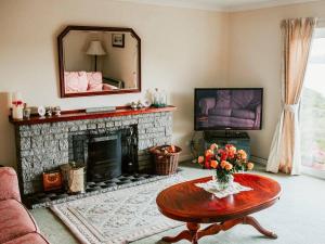 a living room with a fireplace and a table and a mirror at Hollyburn in Breasclete