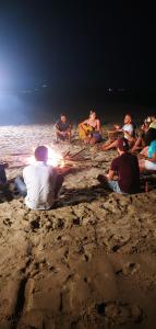a group of people sitting around a fire on the beach at Happy Panda Hostel Arambol Goa in Arambol