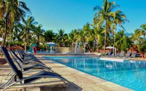 a swimming pool with lounge chairs and palm trees at CAMPO BELO RESORT in Presidente Prudente