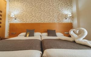 2 camas en una habitación de hotel con camas de cisne en Peregrina Hotel, en Sanxenxo 78 fotos más