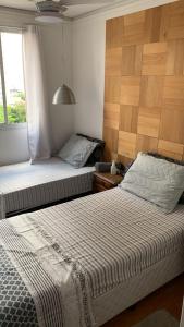 two beds in a small room with a window at Quartos Vila Augusta/Guarulhos in Guarulhos