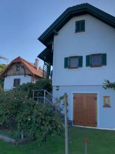 Kulm im Burgenland的住宿－Kellerstöckl Postrumer Weinberg 49，一间白色的房子,有棕色的门和一座建筑