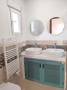 a bathroom with two sinks and two mirrors at Casa La Aurora in Arenas