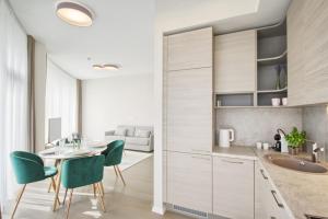 a kitchen with white cabinets and a table and chairs at Apartment DoMiSol in Druskininkai