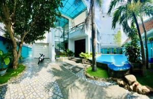 a house with a swimming pool and palm trees at Xoài Xanh Hostel & Villa in Vung Tau