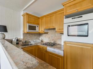 eine Küche mit Holzschränken und einem weißen Kühlschrank in der Unterkunft Appartement Courchevel 1650, 2 pièces, 5 personnes - FR-1-514-65 in Courchevel