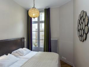 a bedroom with a bed and a window and a chandelier at Bord'ôappart Le Cheverus in Bordeaux