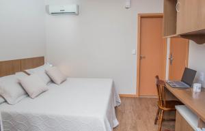 ウルグアイアナにあるHotel Monte Carloのベッドルーム1室(ベッド1台、ノートパソコン付きのデスク付)