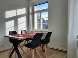 mesa de comedor con 4 sillas y ventana en Jaekels Ferienwohnung en Görlitz