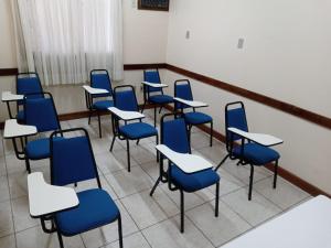 uma sala de aula vazia com cadeiras azuis e secretárias em Hotel Monte Carlo em Uruguaiana