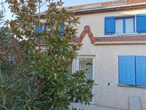 une maison avec des fenêtres bleues et un arbre dans l'établissement MASSY VILMORIN Appartement indépendant 3 pieces, à Massy