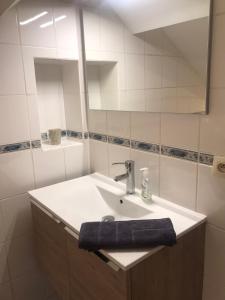 Baño blanco con lavabo y espejo en Logement cosy à Durbuy, en Durbuy