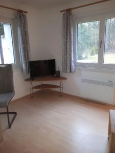 sala de estar con escritorio y 2 ventanas en Ferienhaus am Langen See III en Heidesee