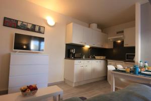 a small kitchen with white cabinets and a table at Appartement SOULAC SUR MER À 500 m de la plage N 5 in Soulac-sur-Mer