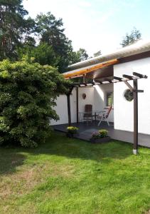 Casa blanca con patio con mesa y sillas en Ferienhaus am Langen See III en Heidesee