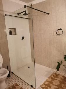 a shower with a glass door in a bathroom at Bono Luxury Guesthouse in Rustenburg