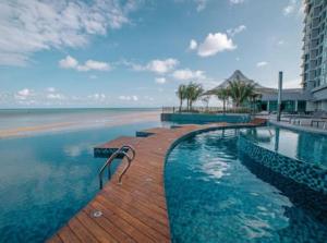 a swimming pool next to a beach with a building at Imperium residence (LA HOMES) in Kuantan