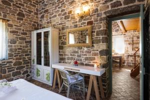 a room with a stone wall with a sink and a mirror at Palaeopoli Villas in Avlemonas