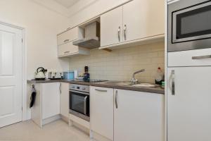 a kitchen with white cabinets and a sink at Top Sail - Beautiful Apartment, Minutes Walk to Beach and Town Centre in Tenby +14 photos