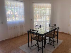 a glass table and chairs in a room with windows at Hotel Galsi in San Felipe de Puerto Plata