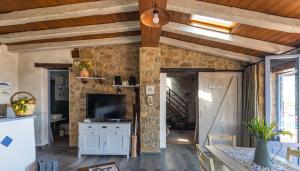 - un salon avec une télévision et un mur en pierre dans l'établissement malandrino cottage, à Cefalù