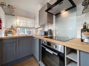 een keuken met blauwe kasten en een fornuis met oven bij 3 Chestnut Terrace, Long Melford in Long Melford