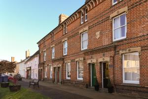 um edifício de tijolos vermelhos com um banco à frente em 3 Chestnut Terrace, Long Melford em Long Melford