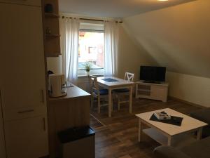 pequeña sala de estar con mesa y cocina en Sommerbrise 2, en Norddeich