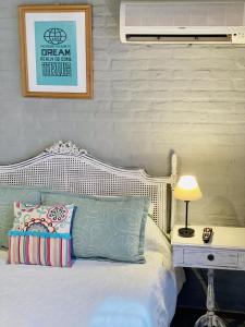um quarto com uma cama branca e um candeeiro sobre uma mesa em VIAJERO Posada & Hostel Punta del este em Punta del Este