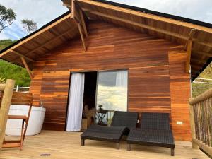 Casa de madera con 2 sillas y patio en Nalua Glamping y Hotel, en San Jerónimo