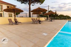 a patio with chairs and umbrellas next to a pool at Alojamento Local Santa Marta in Zebreira