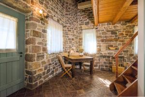 a room with a wooden table and a brick wall at Palaeopoli Villas in Avlemonas