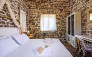 a bedroom with a white bed and a brick wall at Palaeopoli Villas in Avlemonas