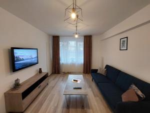 a living room with a blue couch and a tv at Youth Central Apartment in Târgu-Mureş