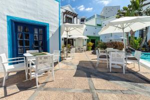 a patio with white chairs and tables and an umbrella at Hotel LIVVO Volcán Lanzarote in Playa Blanca