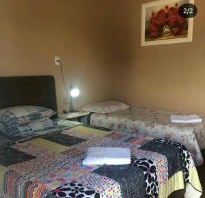 um quarto com duas camas e um candeeiro sobre uma mesa em Pousada Nativa Lages em Lages