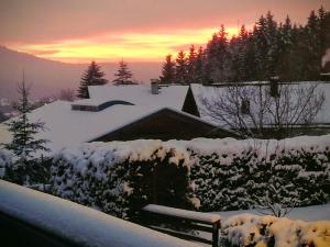 a house covered in snow with a sunset in the background at Hotel Waldhaus in Bodenmais