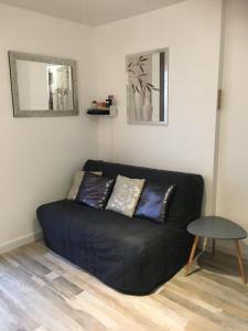 een zwarte bank in een woonkamer met een tafel bij Plage et Mer Service Tout Compris in Cabourg