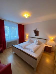 - une chambre avec un grand lit blanc et des rideaux rouges dans l'établissement Apartment Haus C Top 33 -by Four Seasons Apartments, à Kaprun