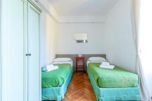 ベッラージョにあるSan Giacomo Central Apartmentの赤いテーブル付きの小さな部屋の緑のベッド2台