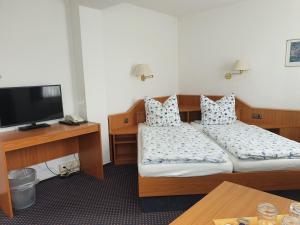 a hotel room with two beds and a flat screen tv at Hotel Störtebeker in Biendorf