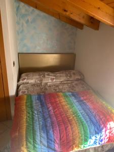 a bed with a rainbow colored blanket on it at Borgo Piccolo in Cavaion Veronese